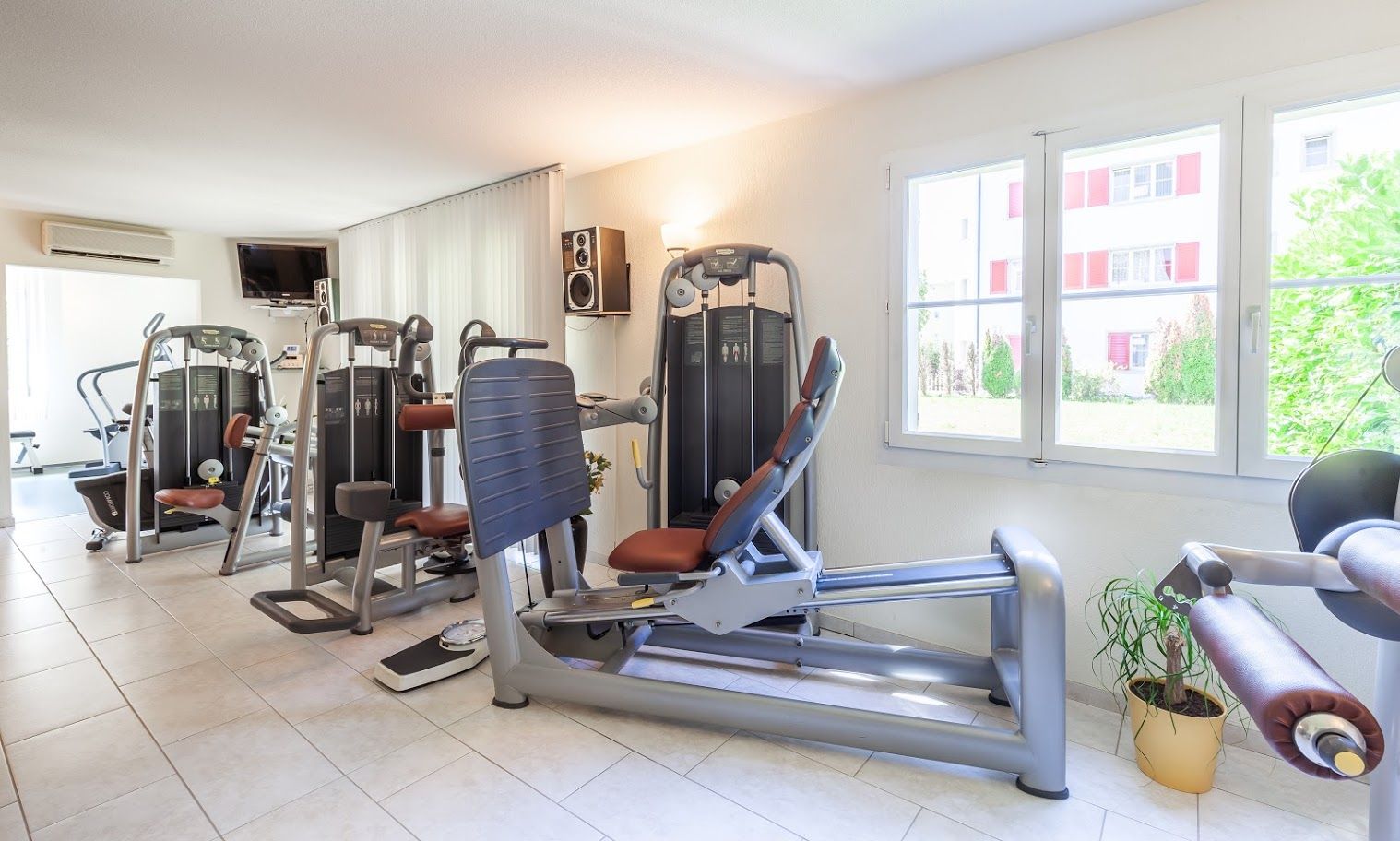 Trainingsfläche mit Beinpresse und Kraftgeräten, Fenster mit Blick ins Grüne